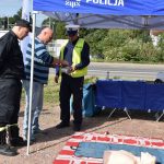 akcja Road Safety Days w Wodzisławiu Śl. 21 wrzesnia 2021 na zdjęciou kierowca przygotowujący się do ćwiczeń pierwszej pomocy w asyście policjanta i strażaka