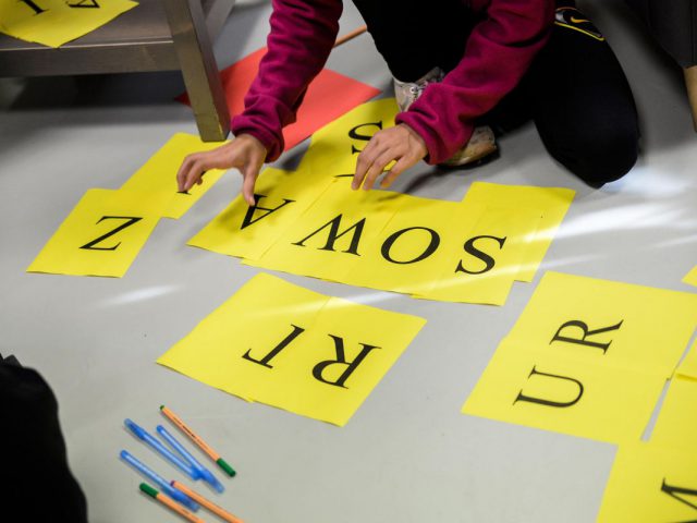 zdjęcie - uczestnicy warsztatów układają słowa z liter na paskach papieru