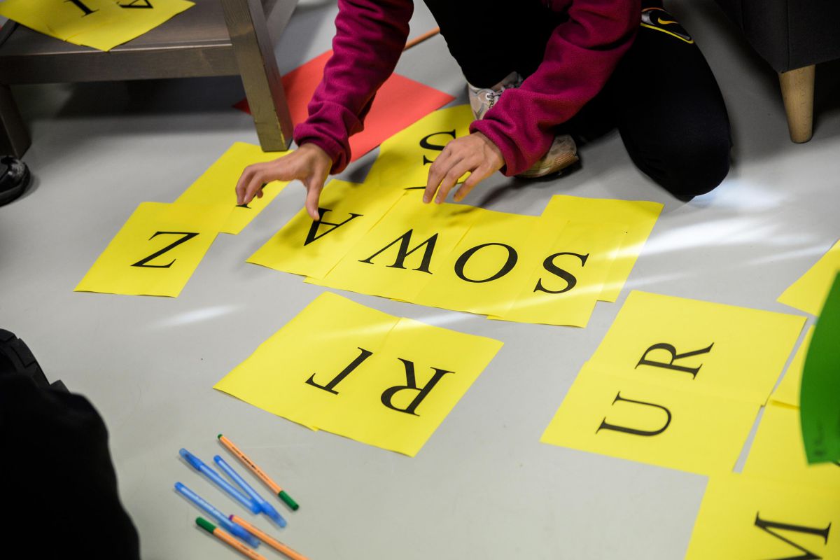 zdjęcie - uczestnicy warsztatów układają słowa z liter na paskach papieru