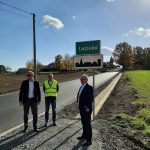 Trzech mężczyzn stojących pod znakiem drogowym z nazwą miejscowości Łaziska, od lewej radny powiatowy Robert Wala, przedstawiciel PZD, starosta Leszek Bizoń