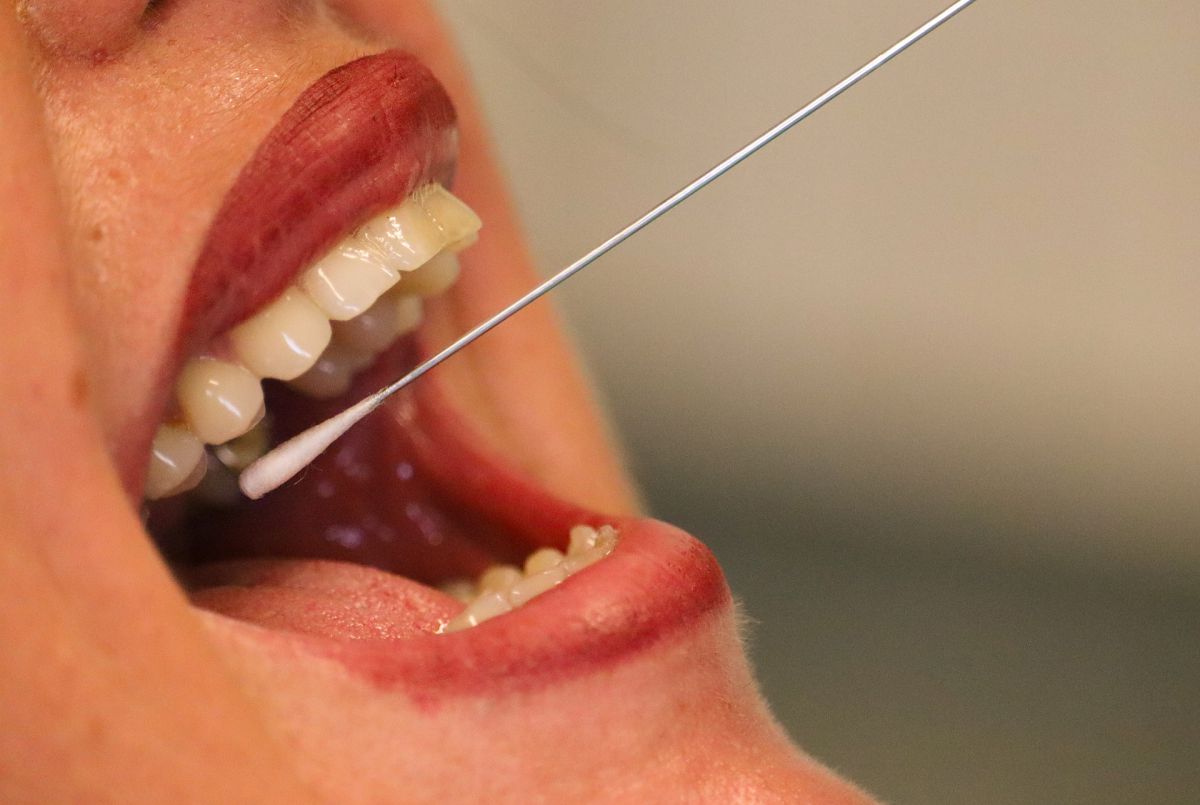 pobieranie wymazu z ust, na zdjęciu owarte usta oraz umieszczony w nich patyczek wymazowy
