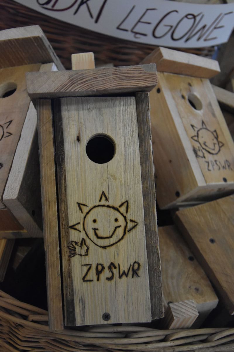Drewniana budka lęgowa z wypalonym logo ZPSWR w kształcie uśmiechniętego słonka