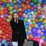 Kobieta śpiewa na scenie, w tle ściana z balonów