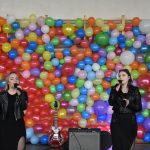 Dwie kobiety śpiewające, w tle ściana z balonów