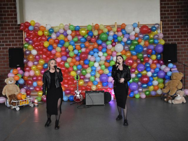Dwie kobiety śpiewające, w tle ściana z balonów