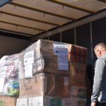 Dary dla Ukraińców - kartony na palecie i jedna osoba pakująca je na ciężarówkę