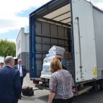 Rozładowanie samochodu ciężarowego z pomocą humanitarną dla uchodźców z Ukrainy, na pierwszym planie pracownicy starostwa odpowiedzialni za rozładunek i rozdysponowanie pomocy