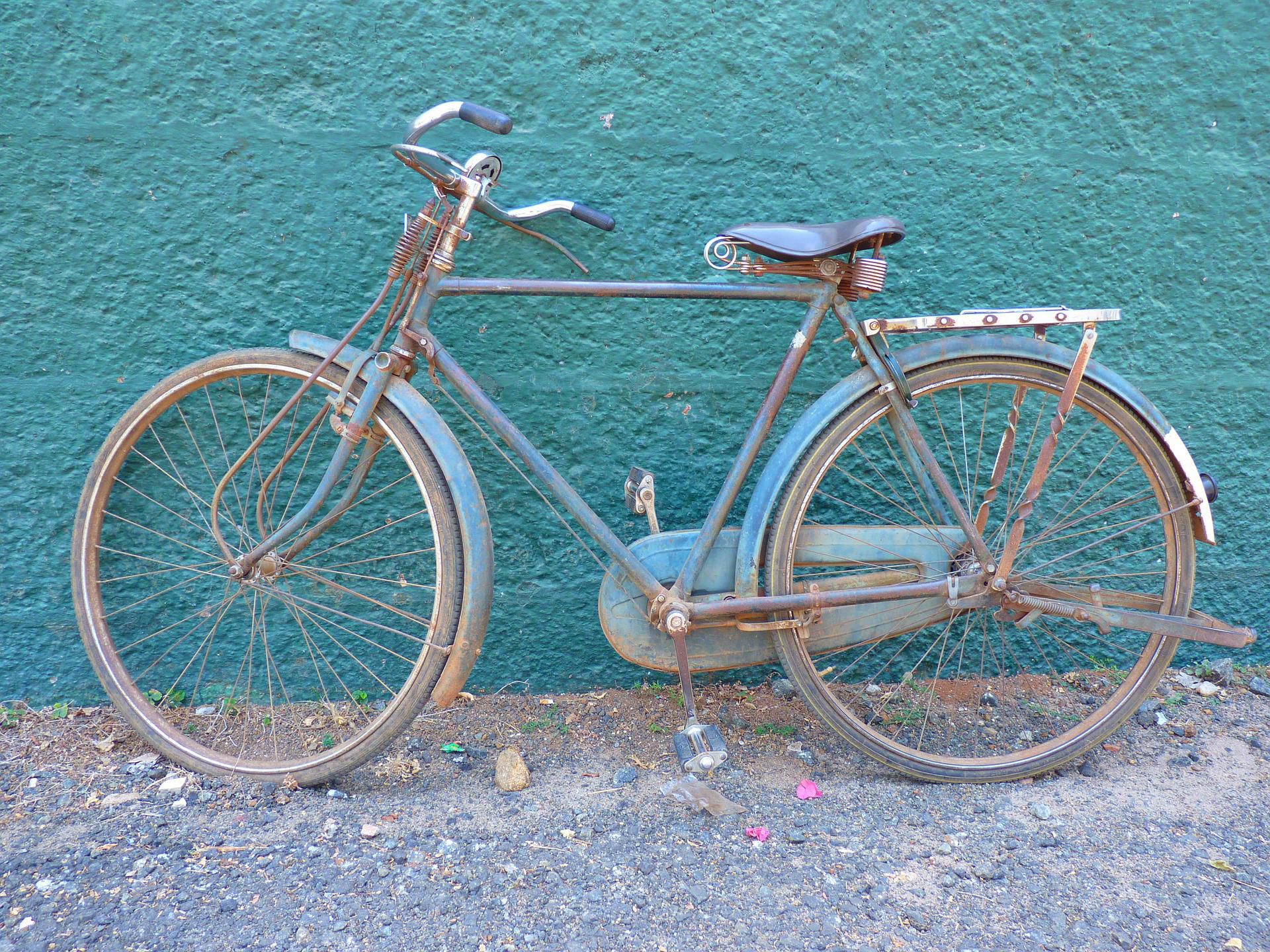 stary rower stojący przed turkusową ścianą