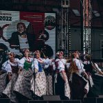 Kobiety przebrane w stroje folklorystyczne tańczą i śpiewają