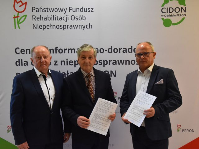 Podpisanie umowy dot. dofinansowania zakupu autobusu, na zdjęciu starosta Bizoń, dyrektor Broński, starosta Bizoń, w tle tablica promocyjna PFRON