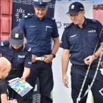 Policjanci z KPP w Wodzisławiu Śląskim wręczający materiały profilaktycze chłopcu