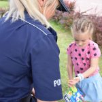 Policjantka z KPP w Wodzisławiu Śląskim wręczający materiały profilaktycze dziewczynce