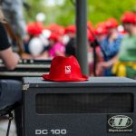 Czerwony kapelusz leży na głośniku. W tle tańczący uczestnicy.