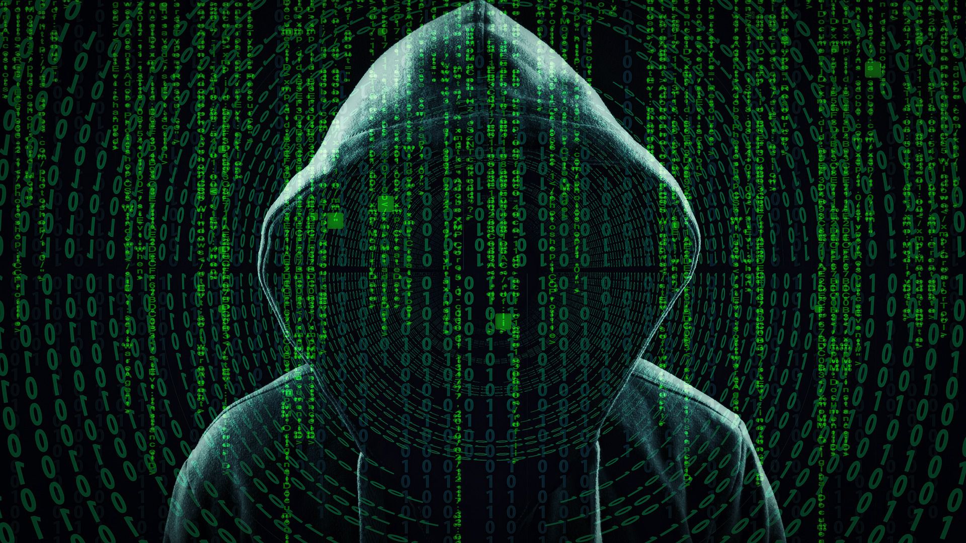 zakapturzona postać ludzka, na pierwszym planie ciągi cyfr i liczb; całość symbolizuje hakera w sieci