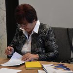 Anna Słotwińska-Plewka podpisuje dokumenty.
