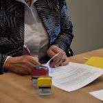 Anna Słotwińska-Plewka podpisuje dokumenty. Zbliżenie na ręce.