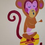Namalowana na ścianie brązowo-różowa małpka.