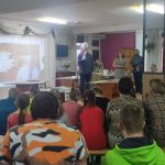 Remigiusz Rączka w stroju szefa kuchni opowiada zebranym uczniom historie związane ze swoją medialną działalnością
