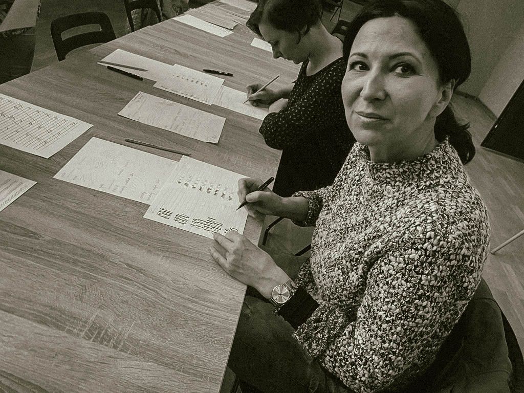 Zdjęcie kobiety siedzącej przy stole, piszącej po kartce