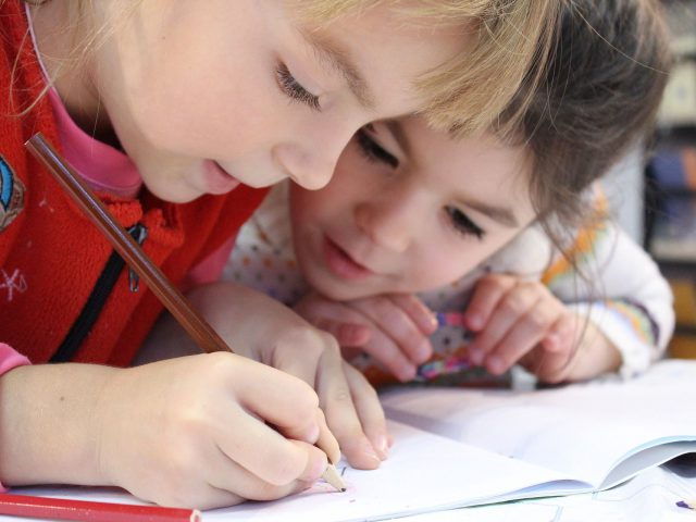 Dwie dziewczynki piszące w zeszycie szkolnym