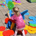 Dziecko budujące rzeźbę z dużych kolorowych klocków