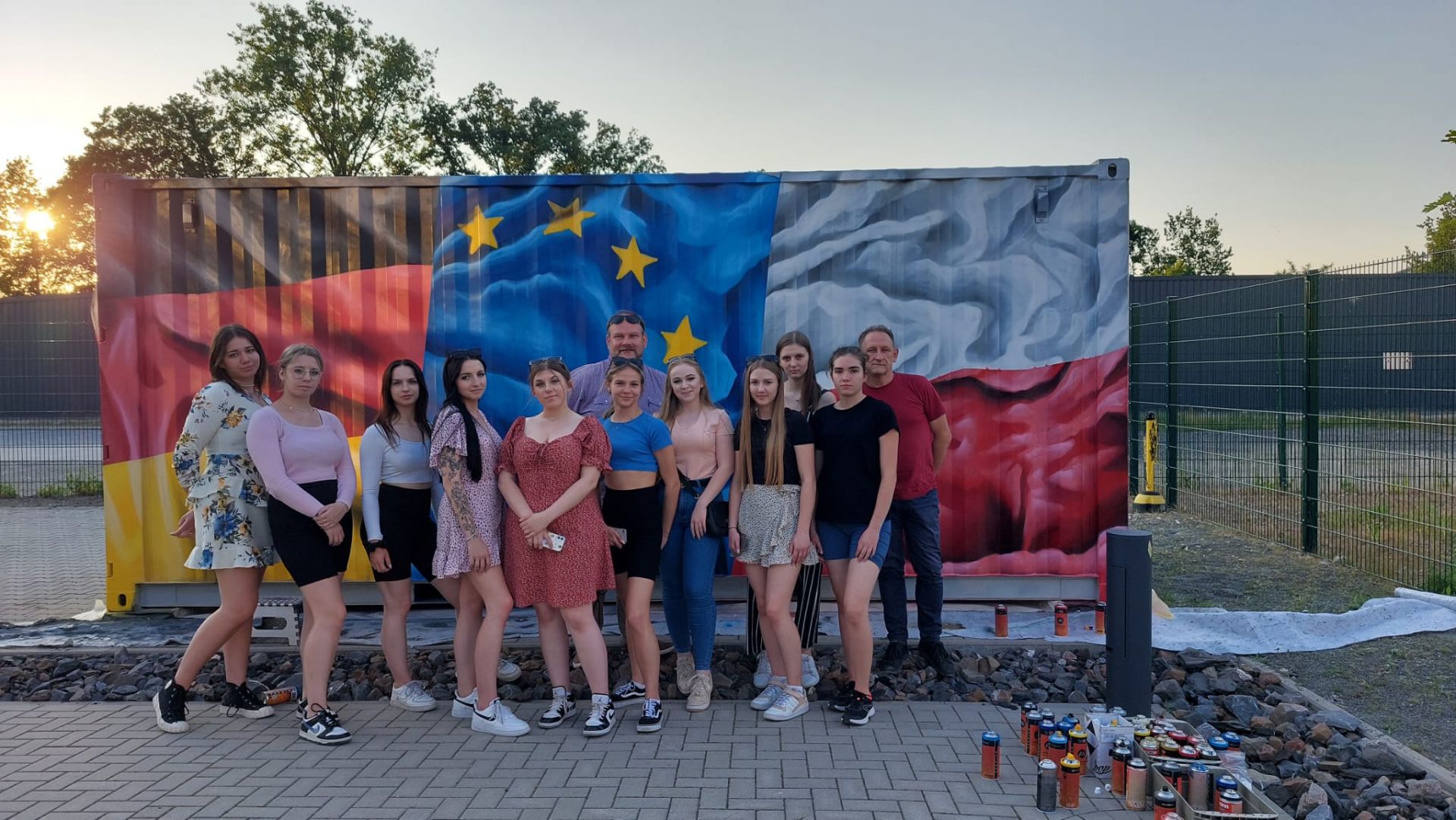 Zdjęcie grupowe młodzieży na tle graffiti w barwach narodowych Polski, Niemiec i UE