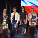 Uczestniczki wydarzenia na scenie, 5 kobiet trzymających róże i teczki z listami gratulacyjnymi