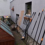Różne narzędzia ogrodnicze stojące rzędem podparte o ścianę