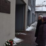 Złożenie kwiatów w miejscach pamięci Ofiar Marszu Śmierci z Auschwitz Birkenau do Wodzisławia Śl. Na zdjęciu 2 postacie ludzkie przed tablicą przy ul. Michalskiego upamiętniającą ofiary Marszu Śmierci