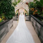 Kobieta ubrana w ekscentryczną artystyczną suknię ślubną wykonaną m.in. z wykorzystaniem żywych kwiatów