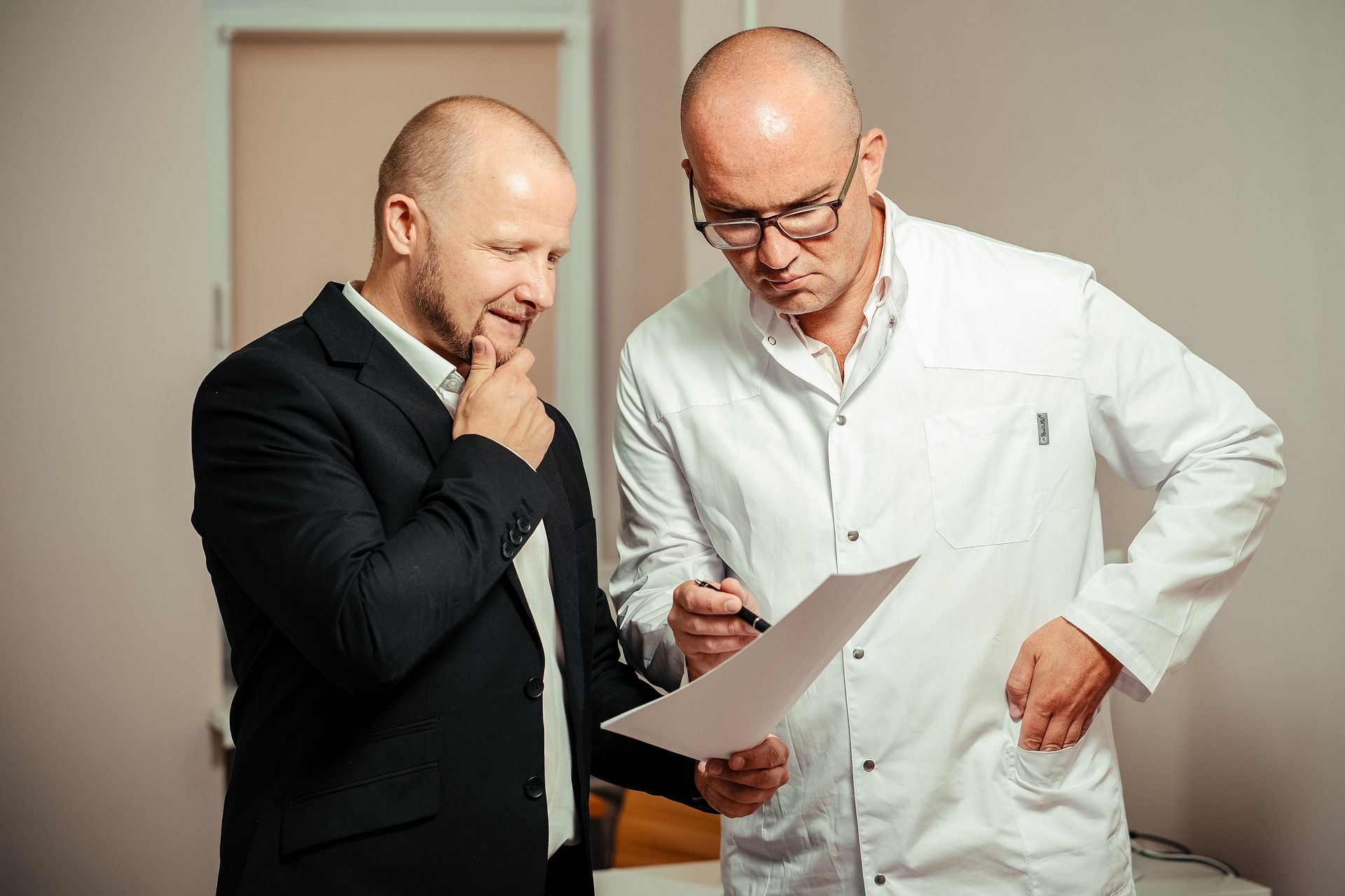 Dwóch mężczyzn, lekarz i pacjent, oglądający kartkę papieru