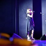 Dziewczyna stoi na scenie i trzyma w ręku mikrofon