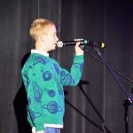 Chłopak trzyma w ręku mikrofon i śpiewa