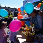 Przedstawicielka powiatu rozdaje dzieciom kolorowe balony