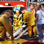 Strażacy prezentują sprzęt do ratowania. Dzieci patrzą