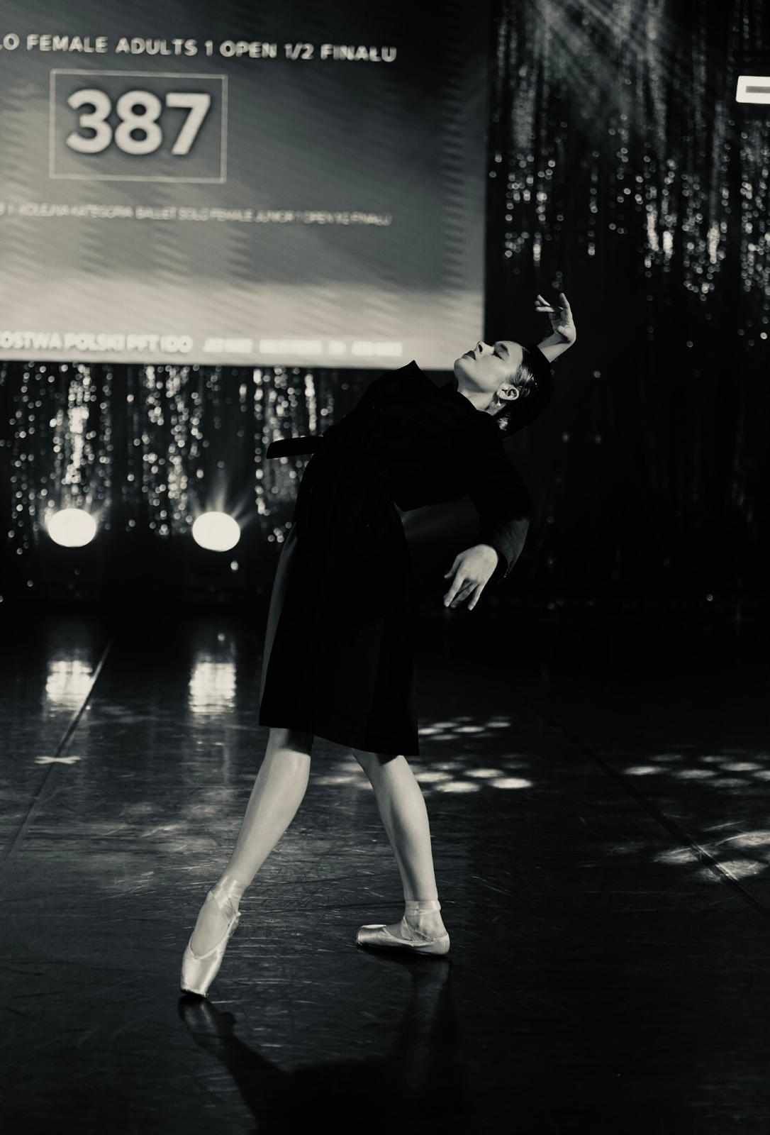 Tancerka tańczy na scenie, zdjęcie jest czarno-białe.